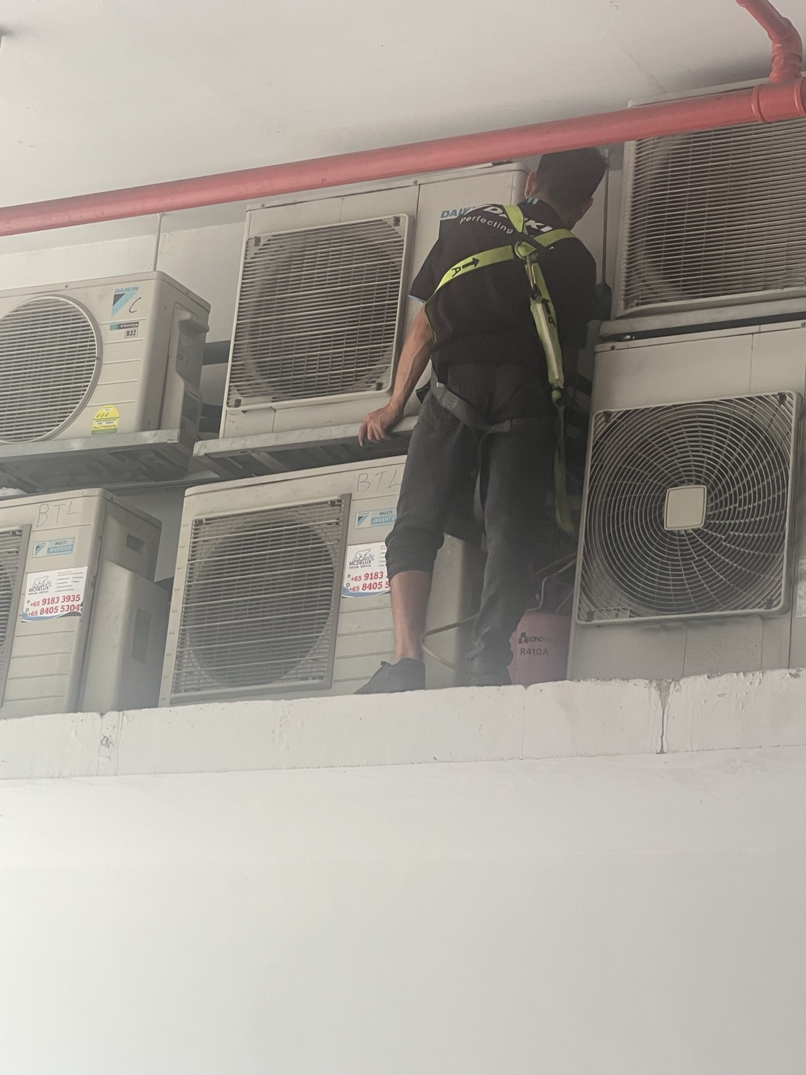 Aircond technician carrying out high-level repair